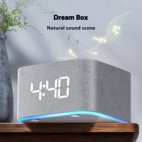 White noise sleep aid with Gray clock with digital display on a wooden surface, featuring the text 'Dream Box Natural sound scene'.